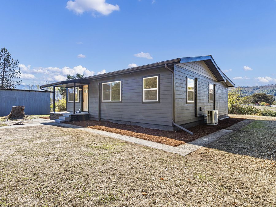 A rebuilt single-story house with new siding, windows, gutters and a covered porch