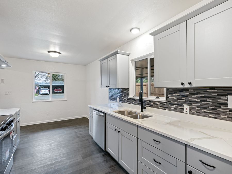 A finished kitchen with new cabinets, counters, tile backsplash and flooring